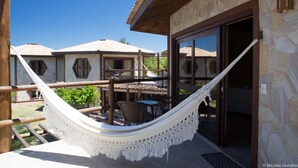 A hammock on a balcony with a view of a building with stone walls and tiled roofs.