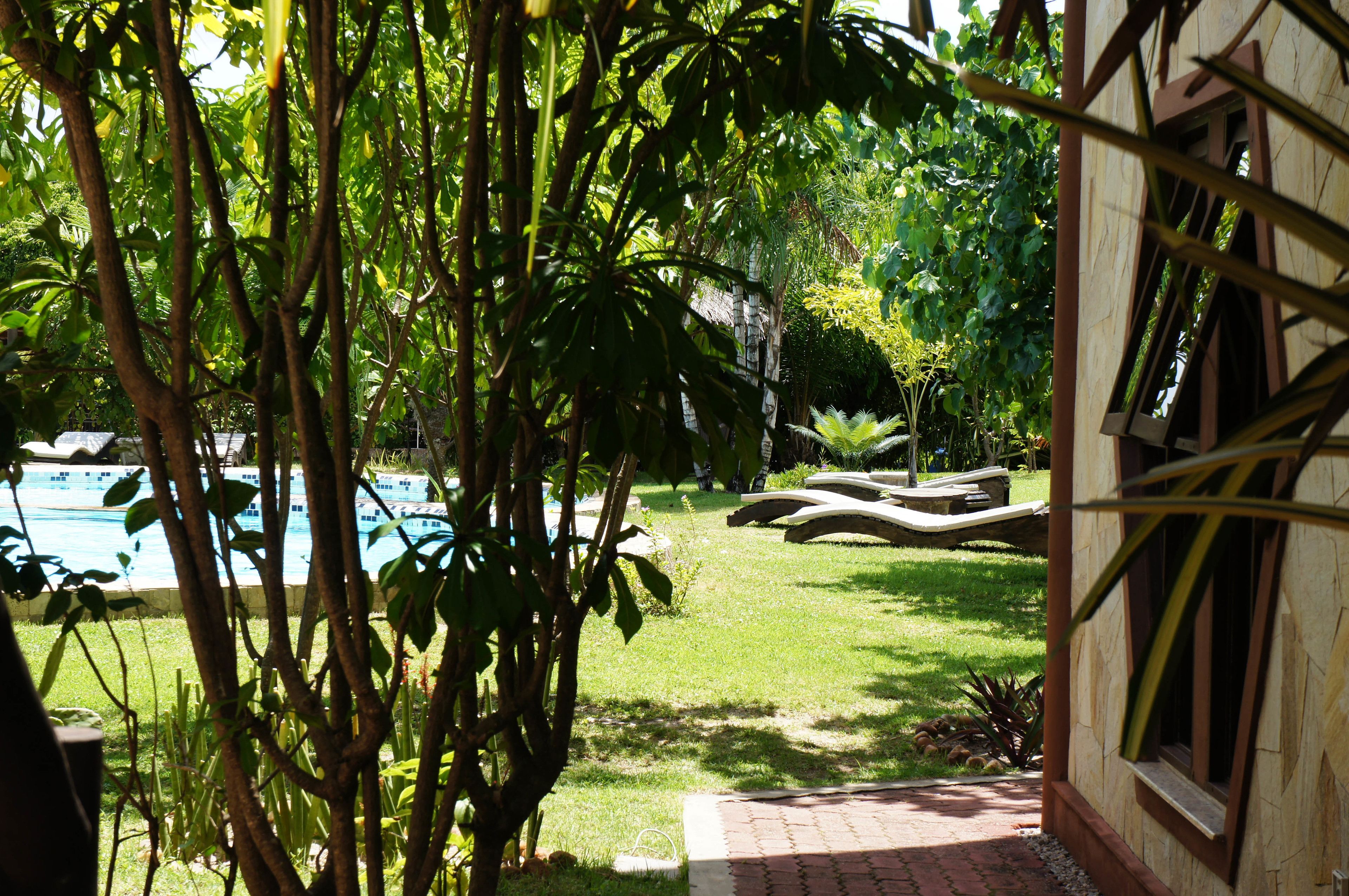 A pool area with lounge chairs and a brick pathway leading to a building.