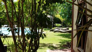 A pool area with lounge chairs and a brick pathway leading to a building.