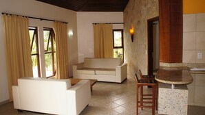 A living room with a sofa, a coffee table, and a dining area with a chair and a small table.