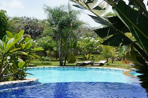 A swimming pool with a tiled edge, surrounded by lush greenery and palm trees. - Morada dos Ventos (Tibau do Sul)
