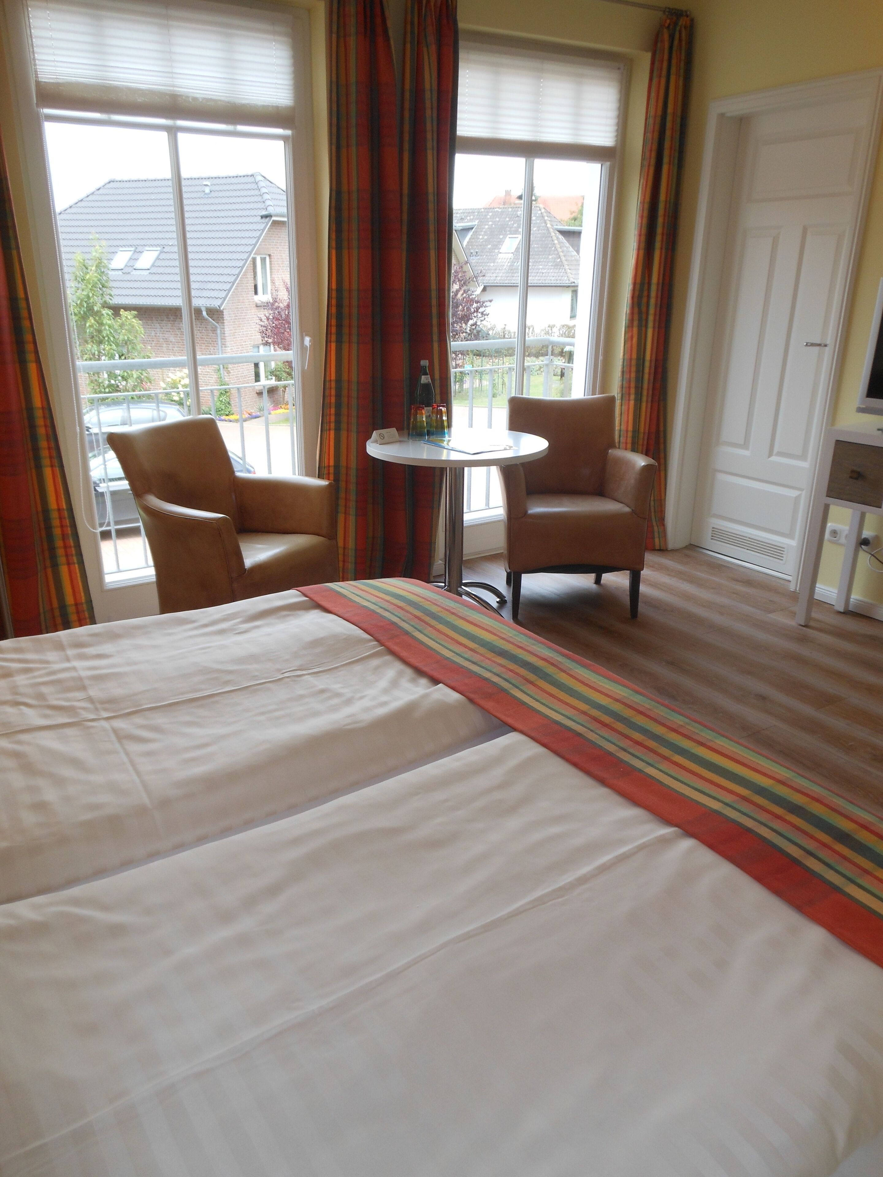 A hotel room with a bed, two armchairs, a small round table, and a television.
