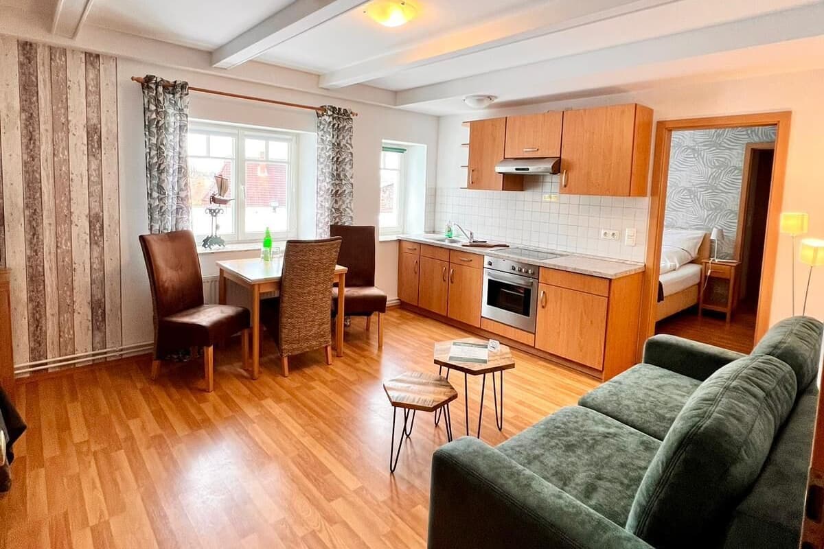 Un espacio habitable compacto con comedor, kitchenette y sofá.