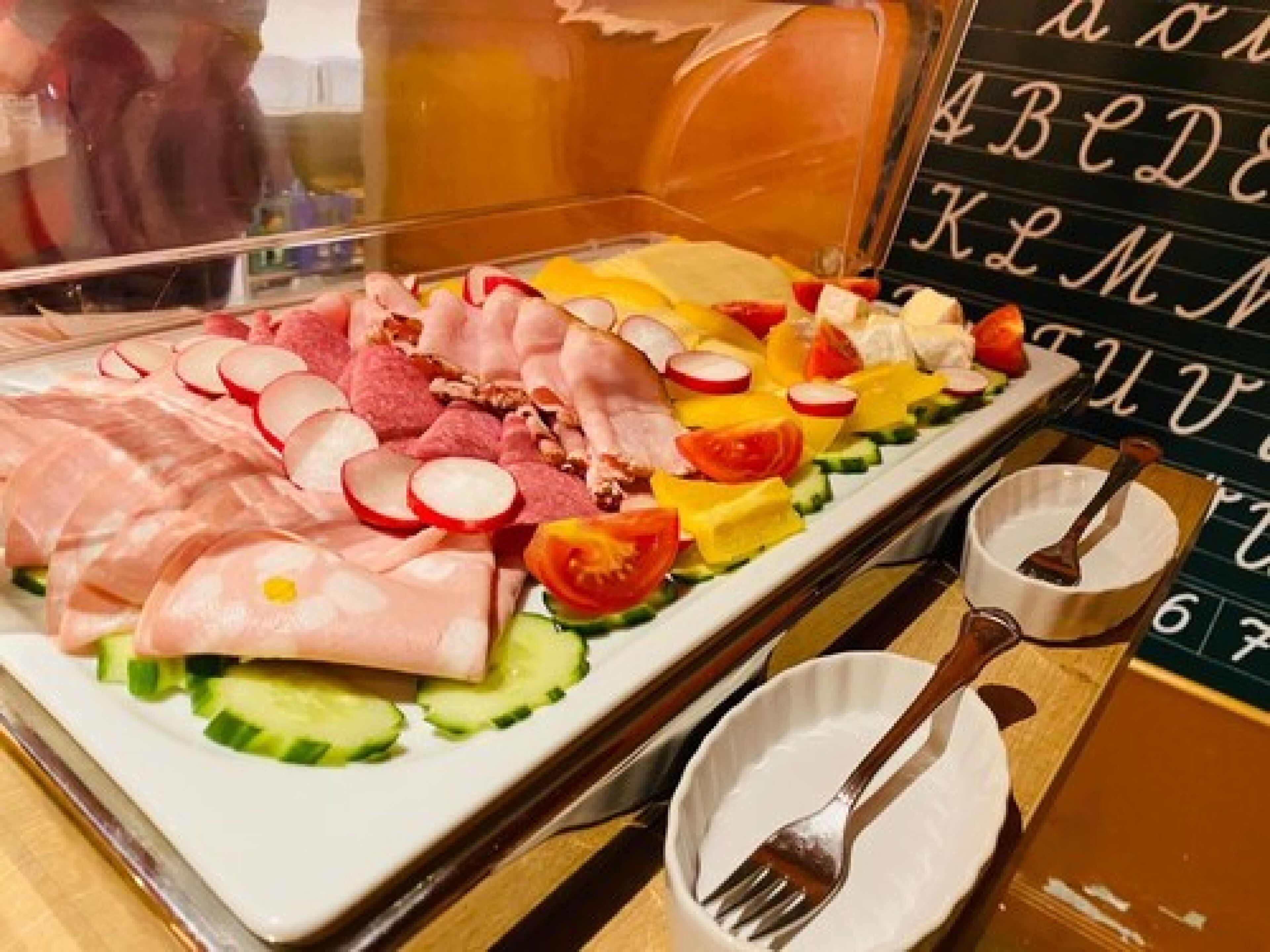 A charcuterie board with various meats, cheeses, and vegetables.