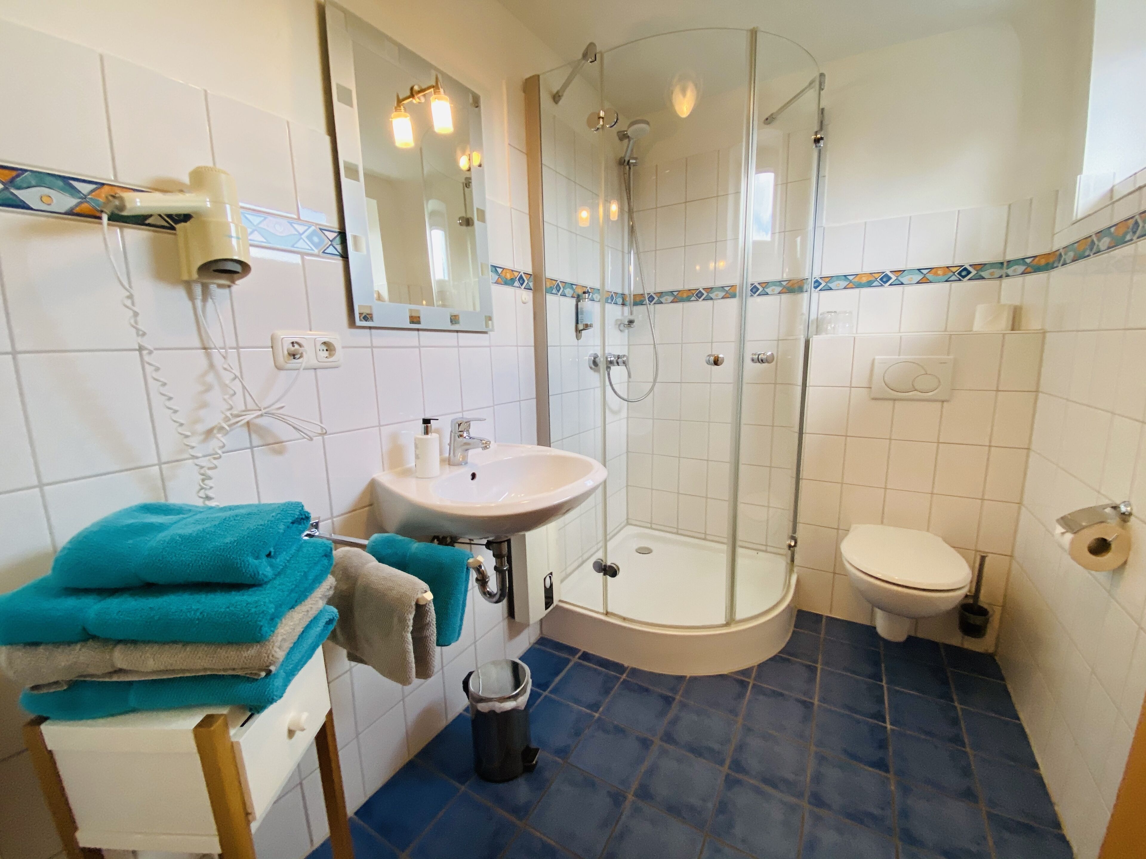 A bathroom with a sink, toilet, and glass-enclosed shower.