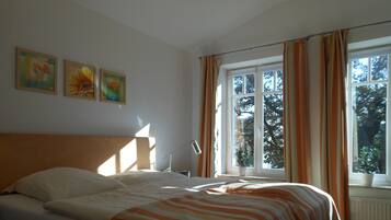 Een slaapkamer met een bed, nachtkastje, lamp en een raam met gordijnen.