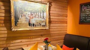 Un comedor con pared de madera, un cuadro enmarcado y un menú en pizarra.