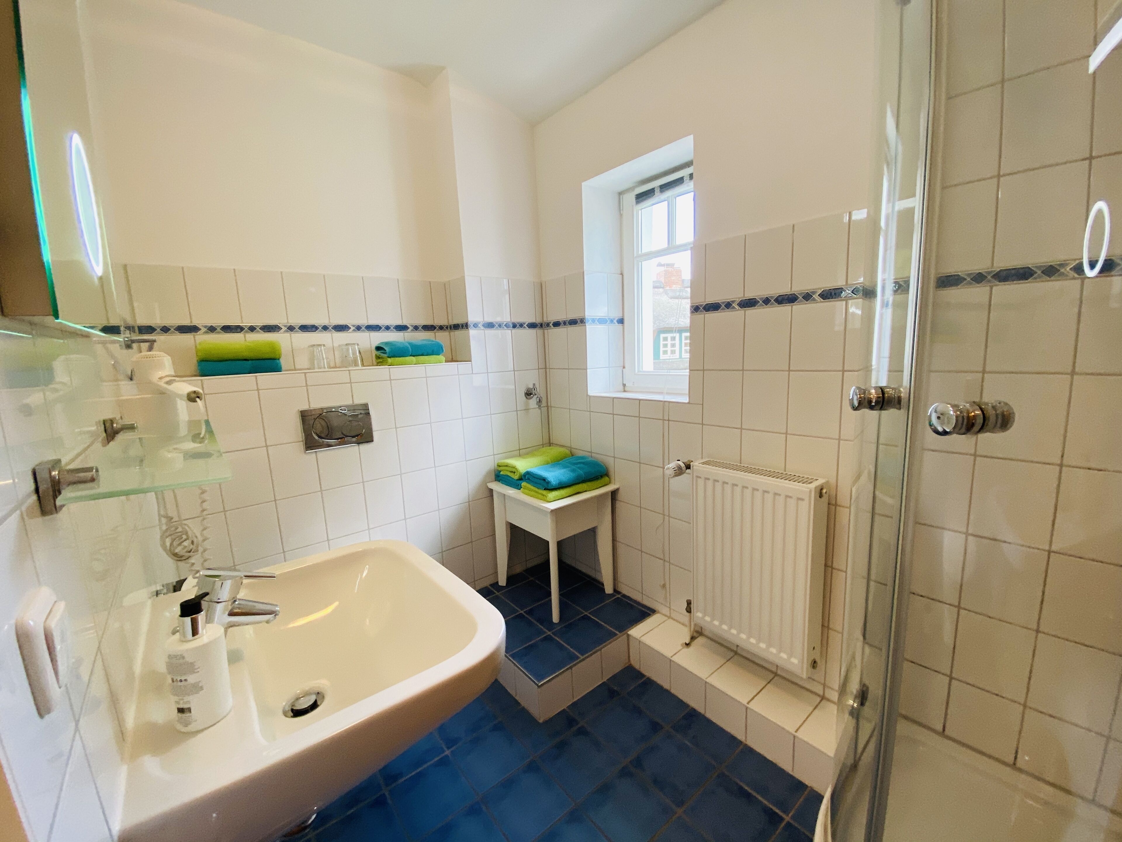 Une salle de bain avec un lavabo, un miroir, un porte-serviettes et une fenêtre.