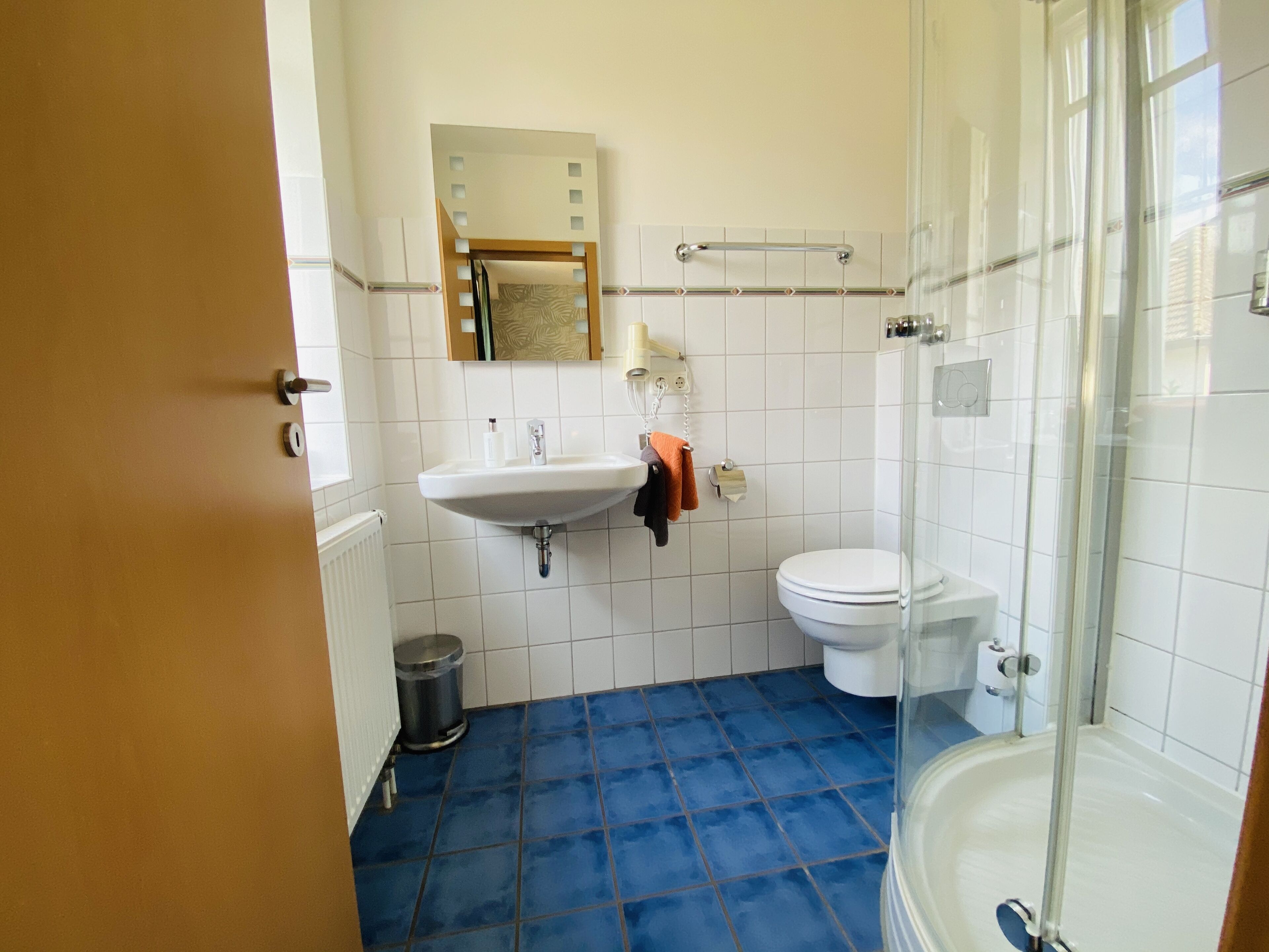 A bathroom with a sink, mirror, toilet, and shower.