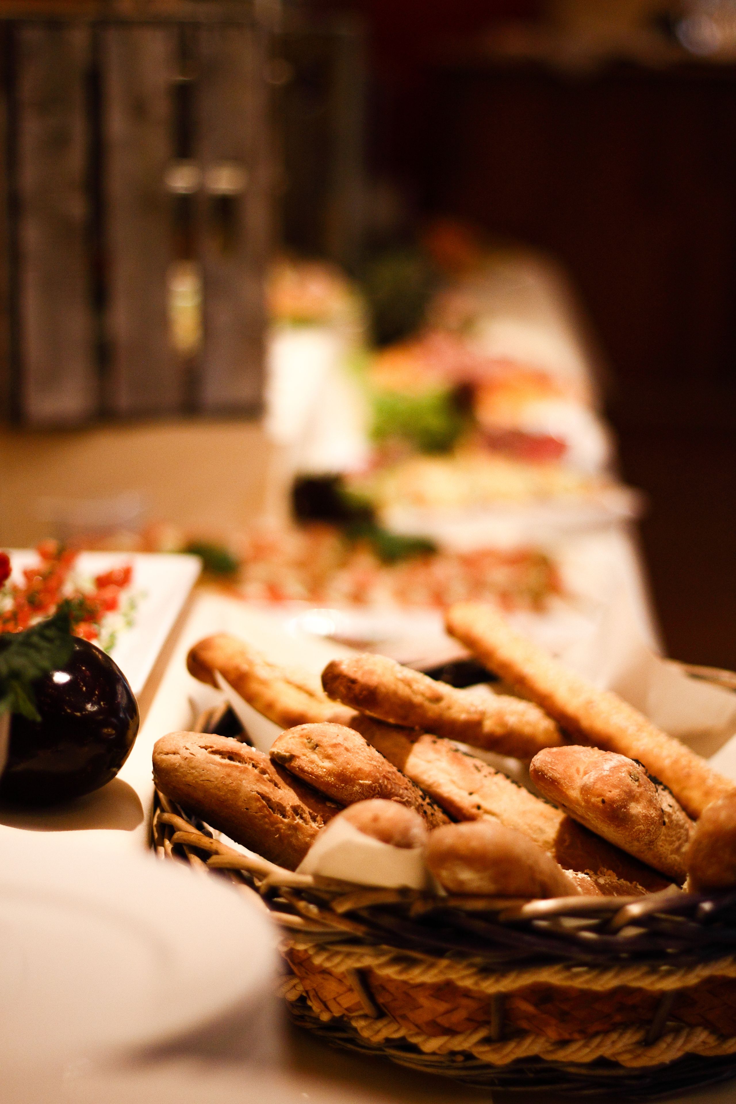 Ein Buffet mit verschiedenen Speisen, darunter Brot und ein Korb mit Baguettes.
