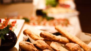 Ein Buffet mit verschiedenen Speisen, darunter Brot und ein Korb mit Baguettes.