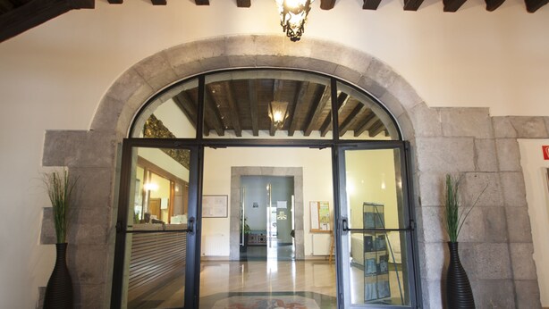 An arched entrance with glass doors, a stone wall, and a tiled floor. - Arrupe (Azpeitia)