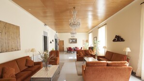 A spacious living room with a high ceiling and a chandelier, featuring orange sofas and a coffee table. - Arrupe (Azpeitia)