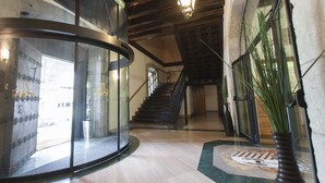 A modern interior with a curved glass elevator, a wooden staircase, and a decorative rug. - Arrupe (Azpeitia)