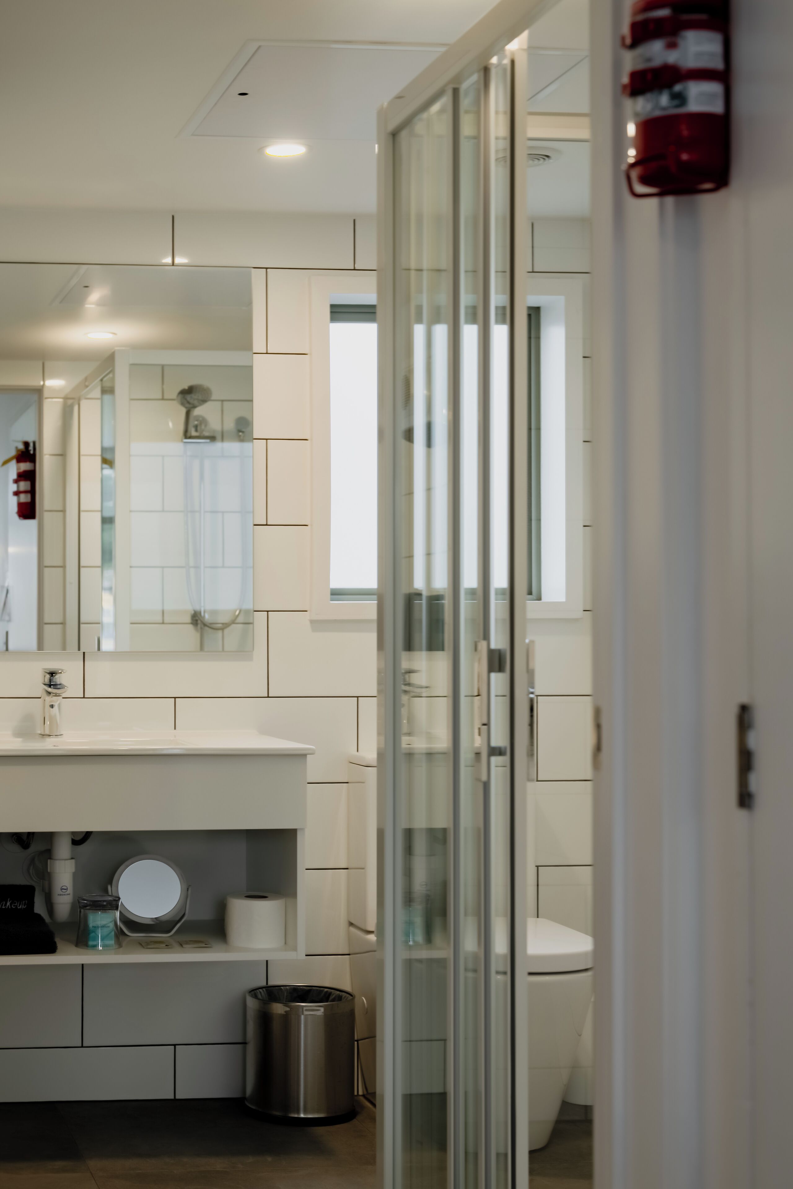 Een moderne badkamer met een douchecabine van glas, een wit wastafelmeubel met spiegel, en een toilet.