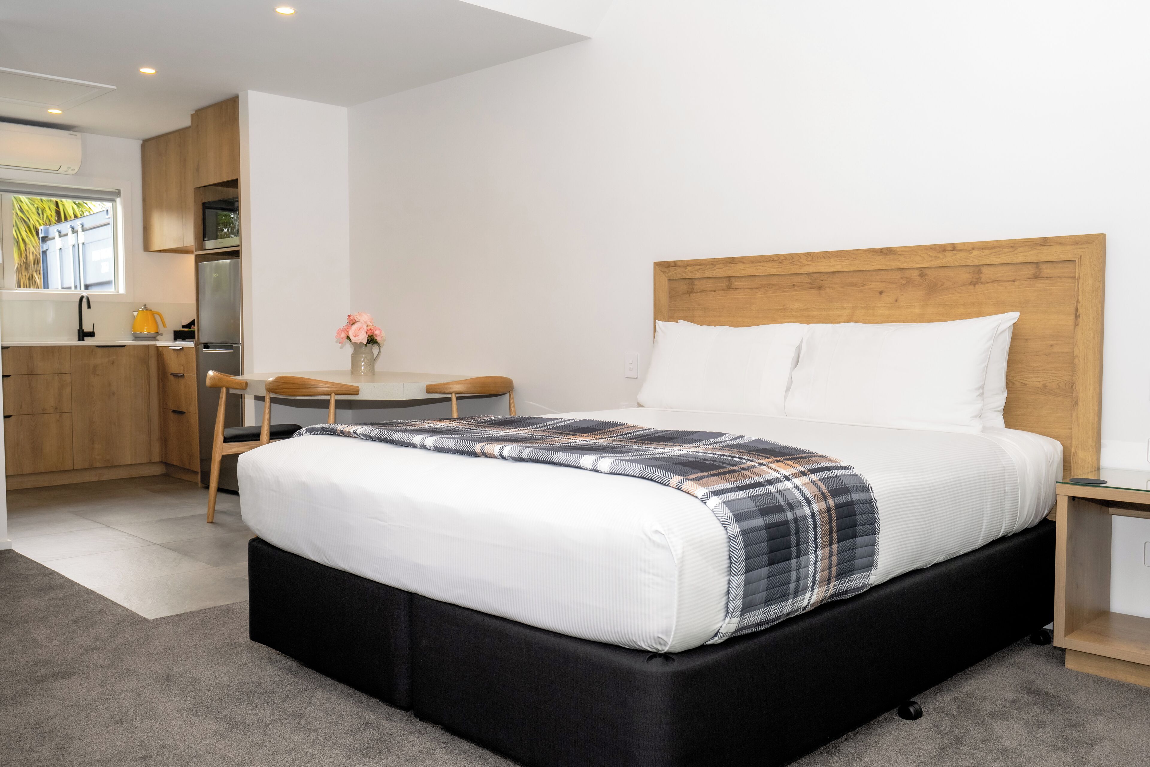 A modern bedroom with a large bed, a wooden headboard, and a small bedside table.