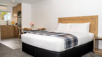 A modern bedroom with a large bed, a wooden headboard, and a small bedside table.