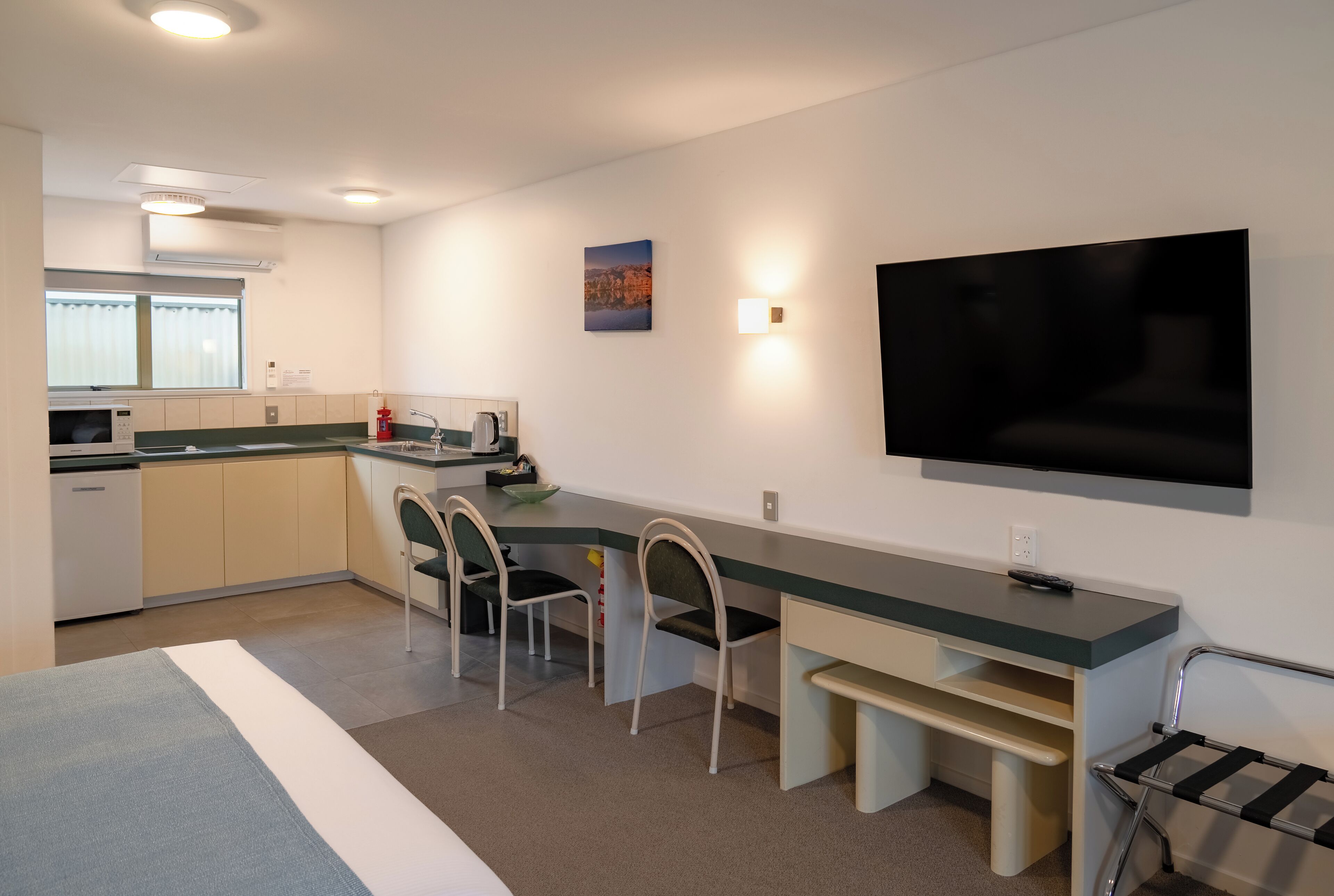 A modern kitchen with a dining area, a flat-screen TV, and a small seating space.