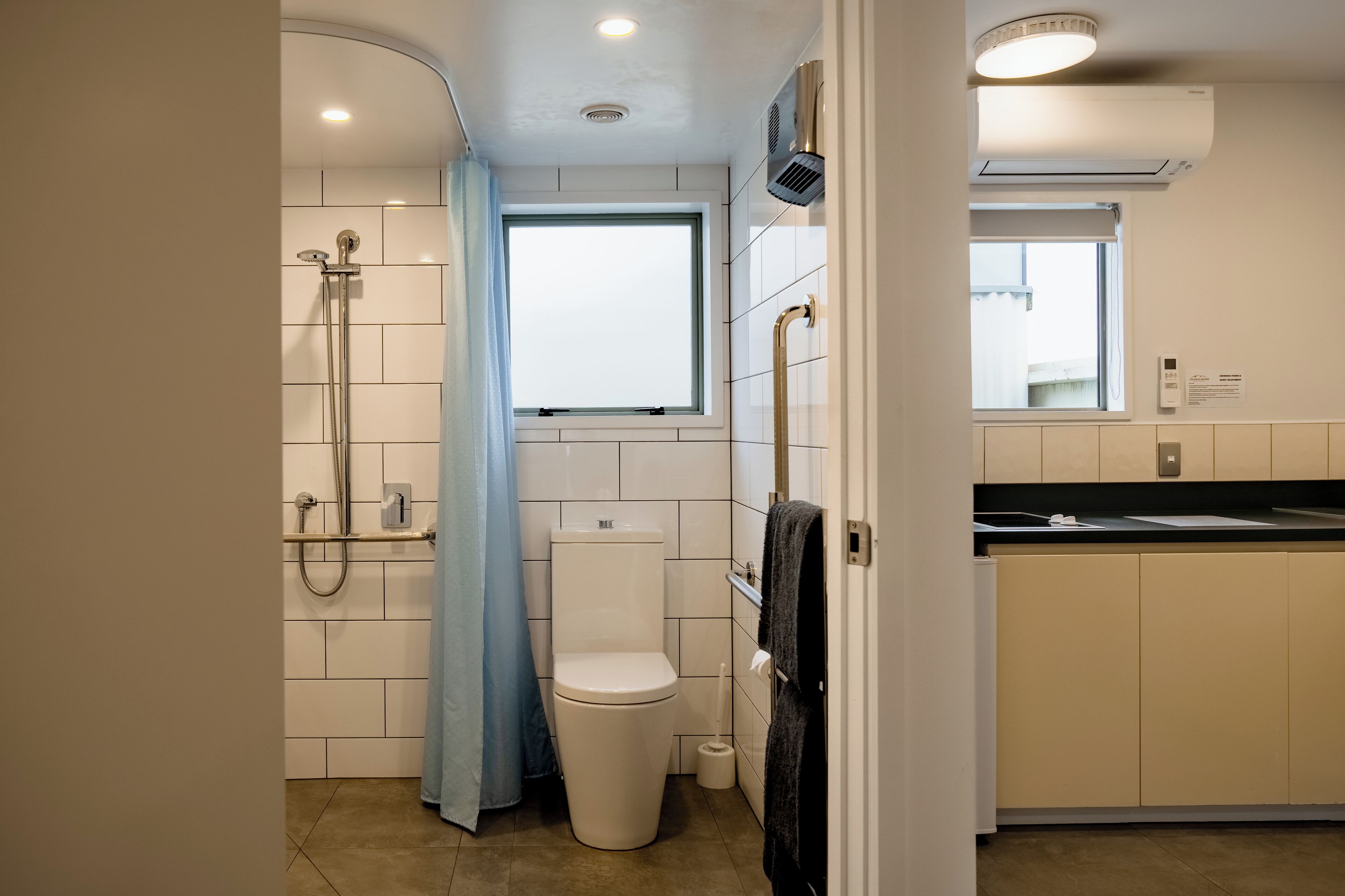 A compact bathroom with a toilet, shower, and a window.