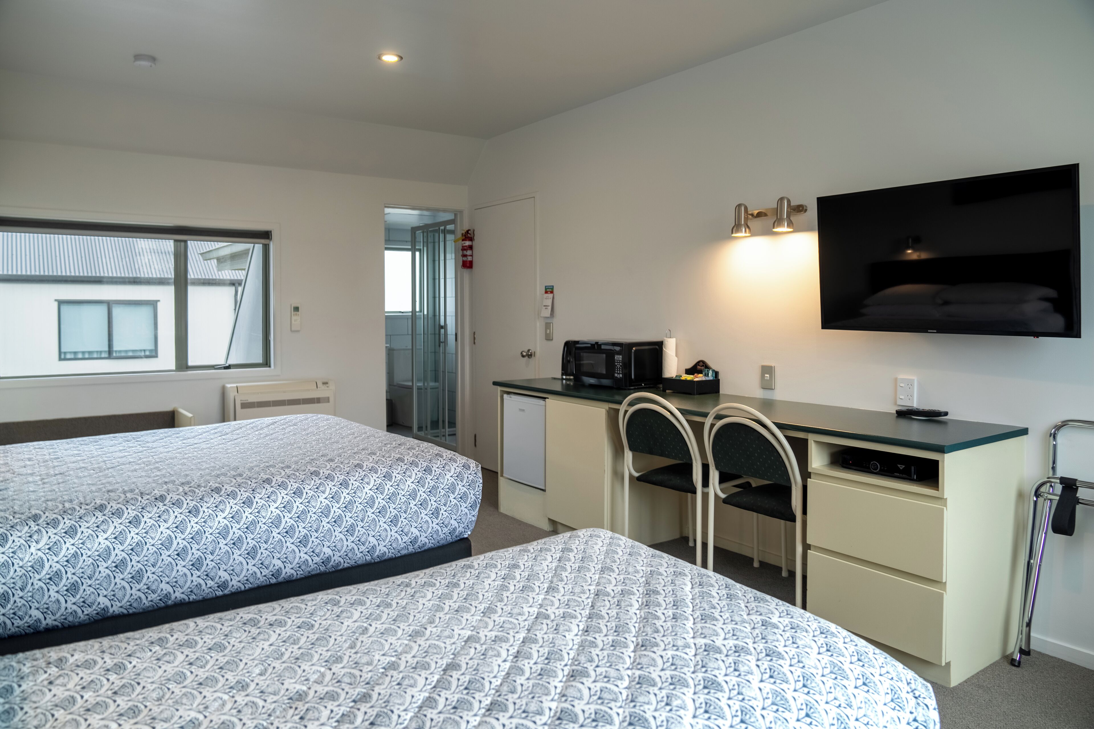 A hotel room with two beds, a desk with a computer, a TV, and a microwave.