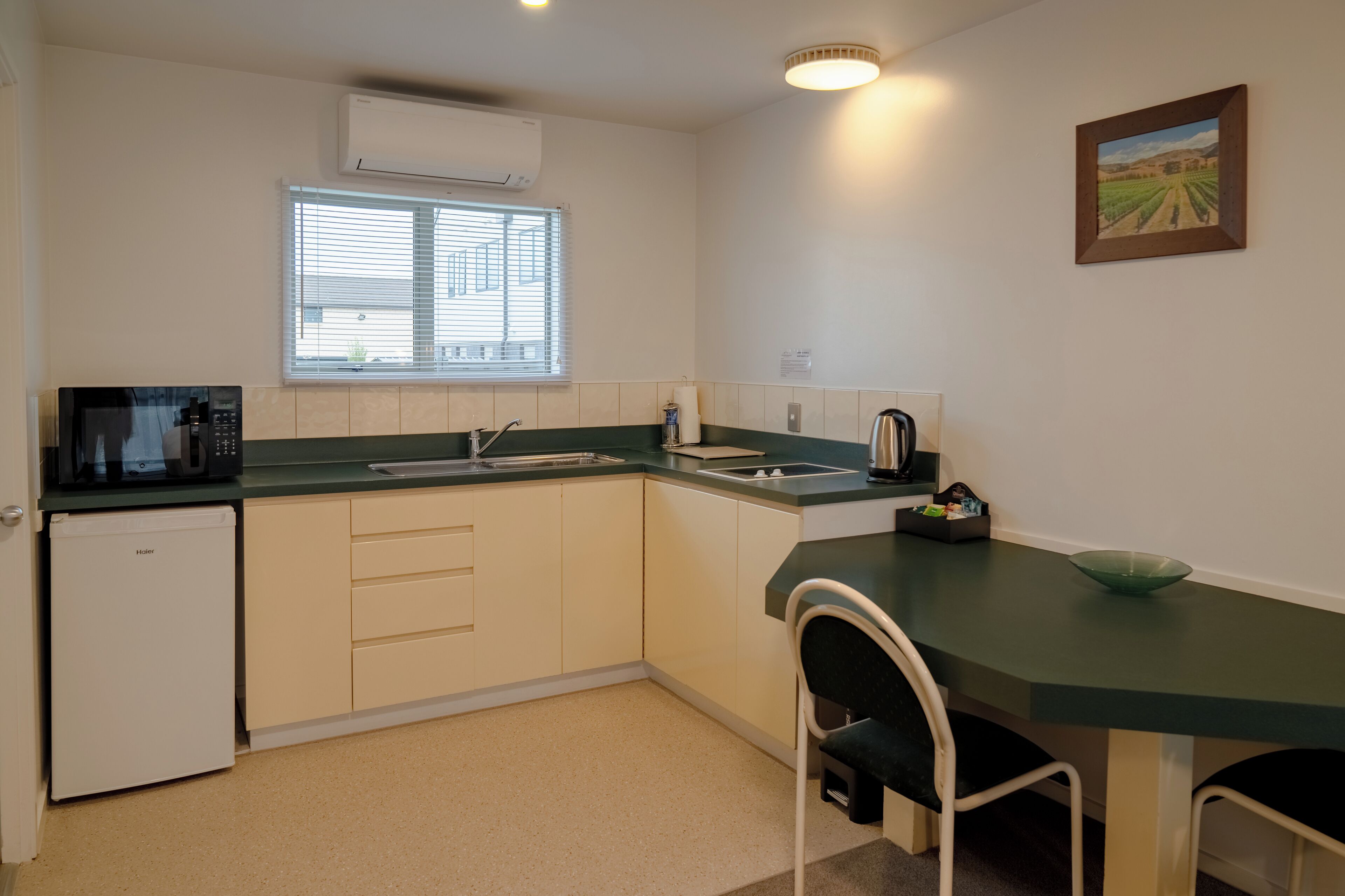 A compact kitchen with a microwave, sink, and a small refrigerator.