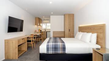 Une chambre d’hôtel moderne équipée d’un lit, d’un bureau et d’une télévision.