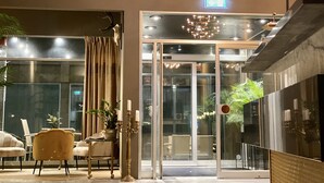 A modern interior with a glass door entrance, a chandelier, and a seating area with chairs and a table. - Palm Tree Hotel, Best Western Signature Collection (Trelleborg)