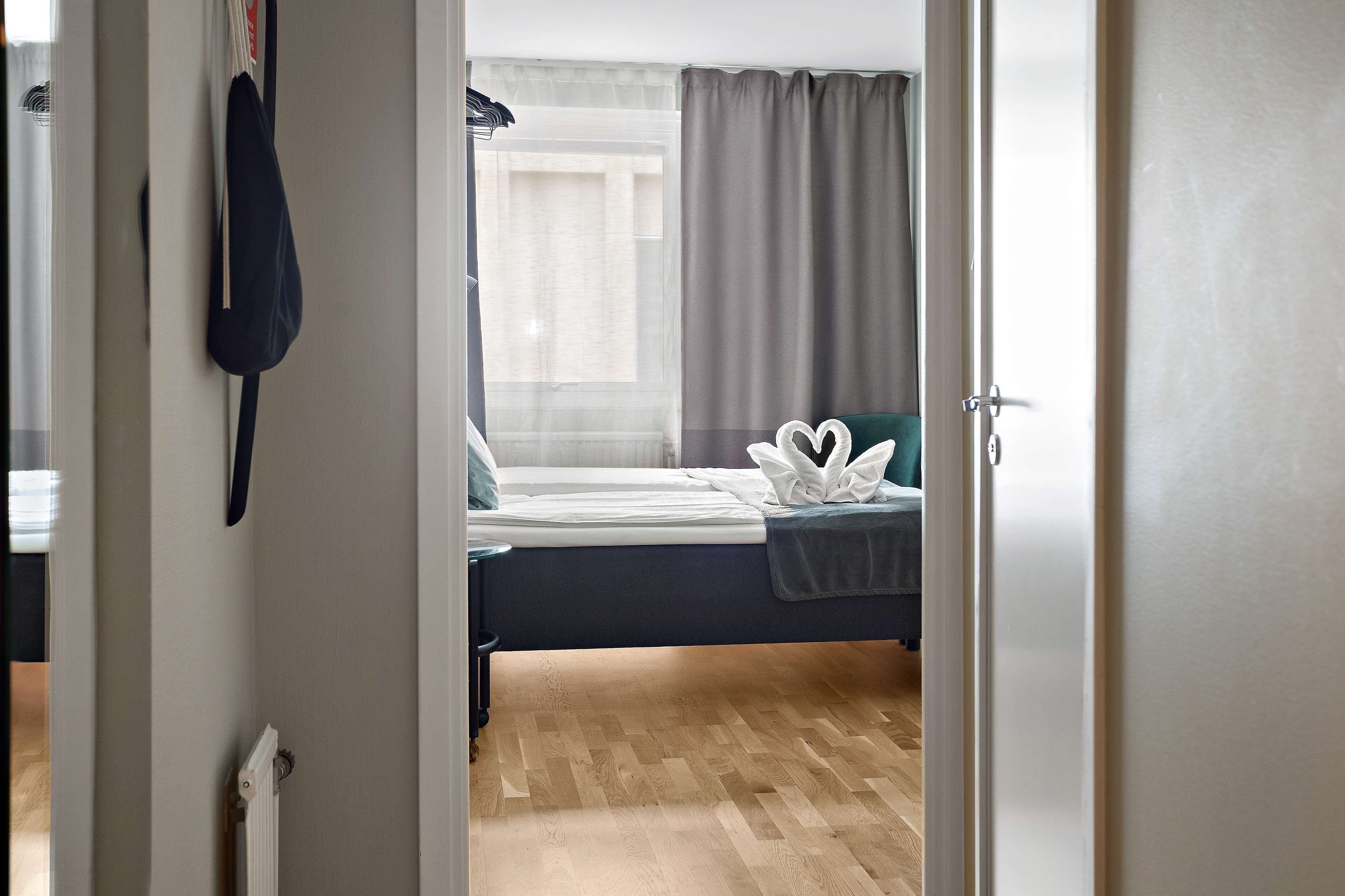 Un dormitorio con cama, radiador, cortina y puerta.