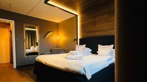 A modern hotel room with a large bed, a mirror, a bedside table, and a wooden floor. - Palm Tree Hotel, Best Western Signature Collection (Trelleborg)