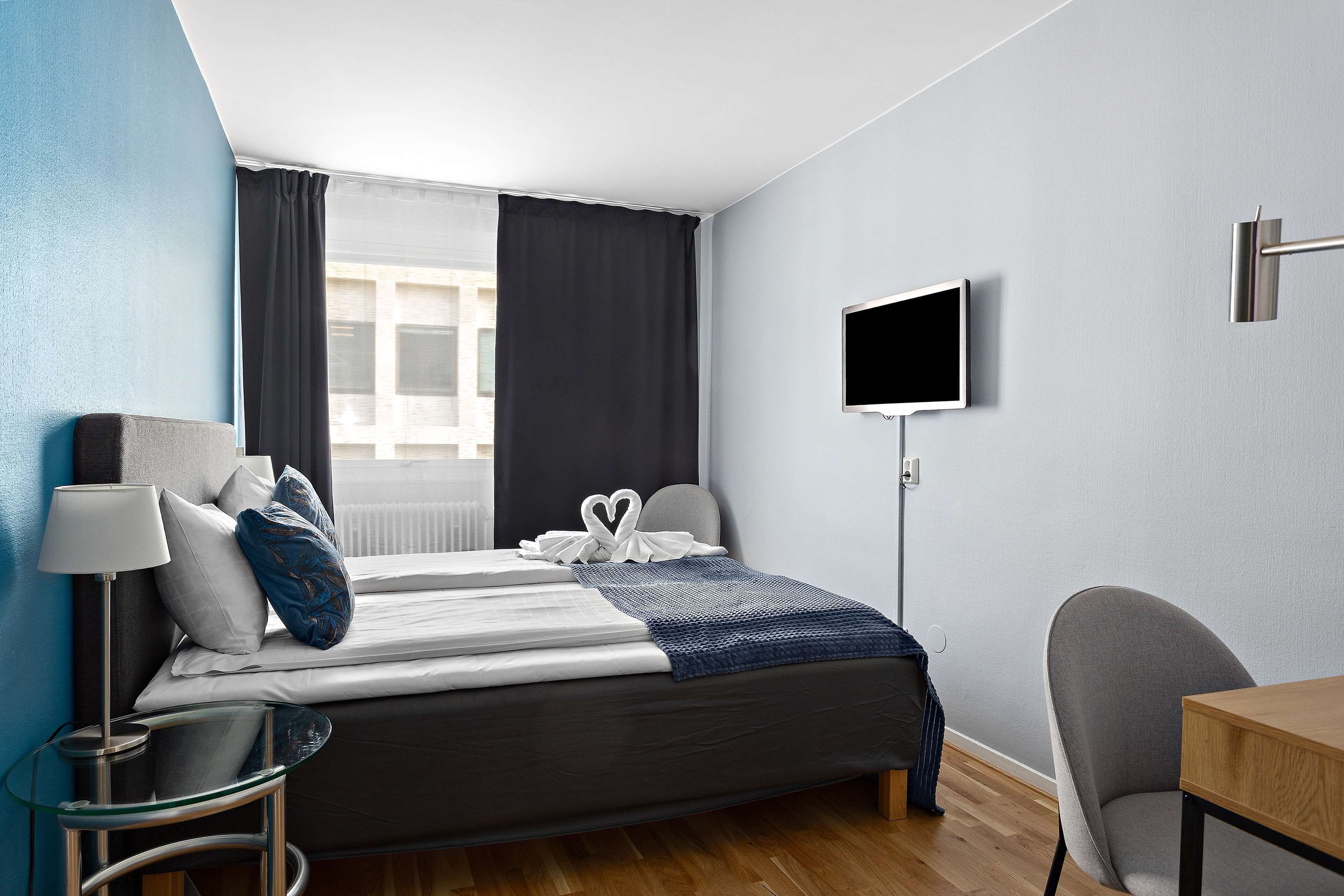 Una habitación de hotel moderna con cama, televisor, escritorio y silla.