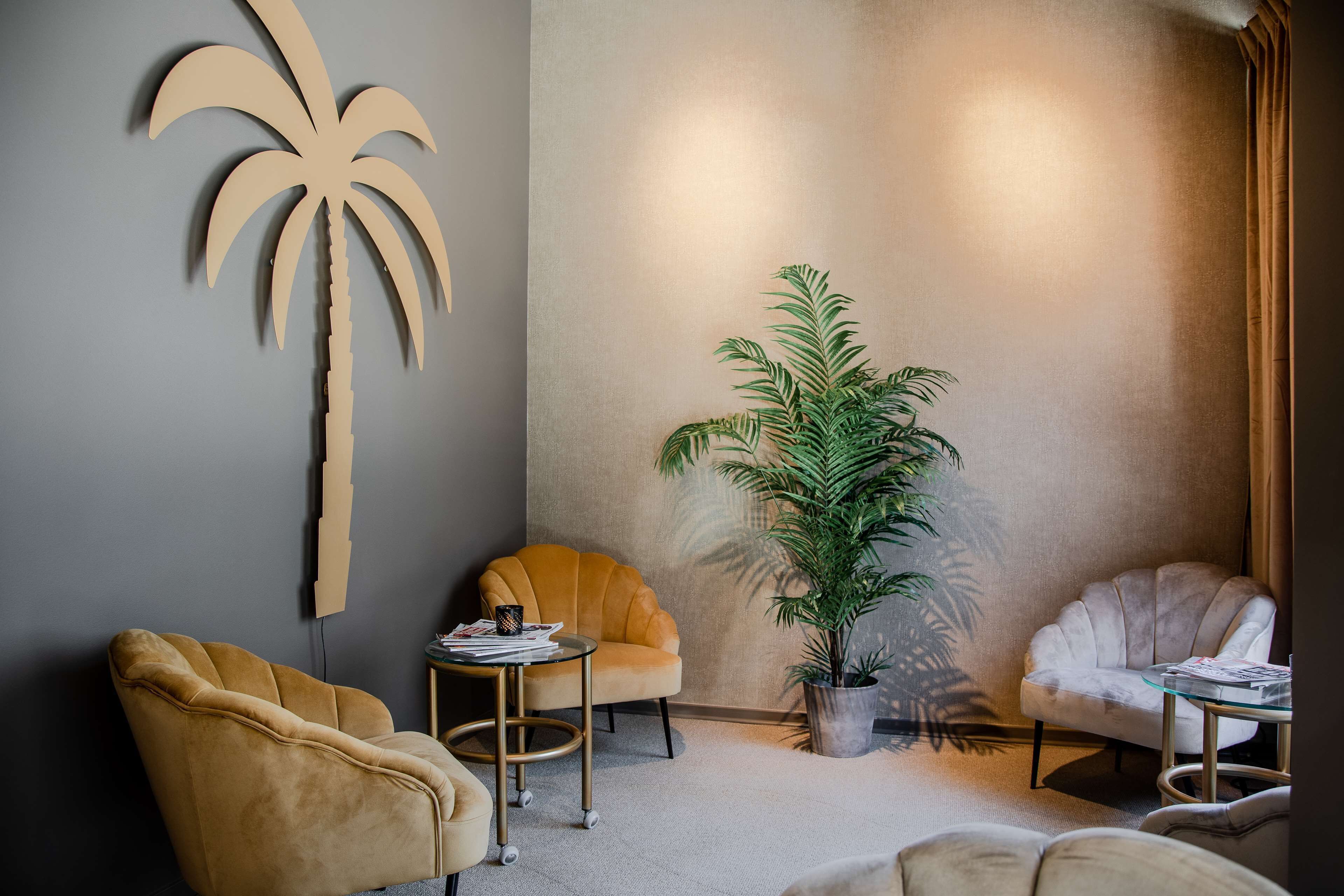 A modern room with a large palm tree decoration, a potted plant, and two armchairs.