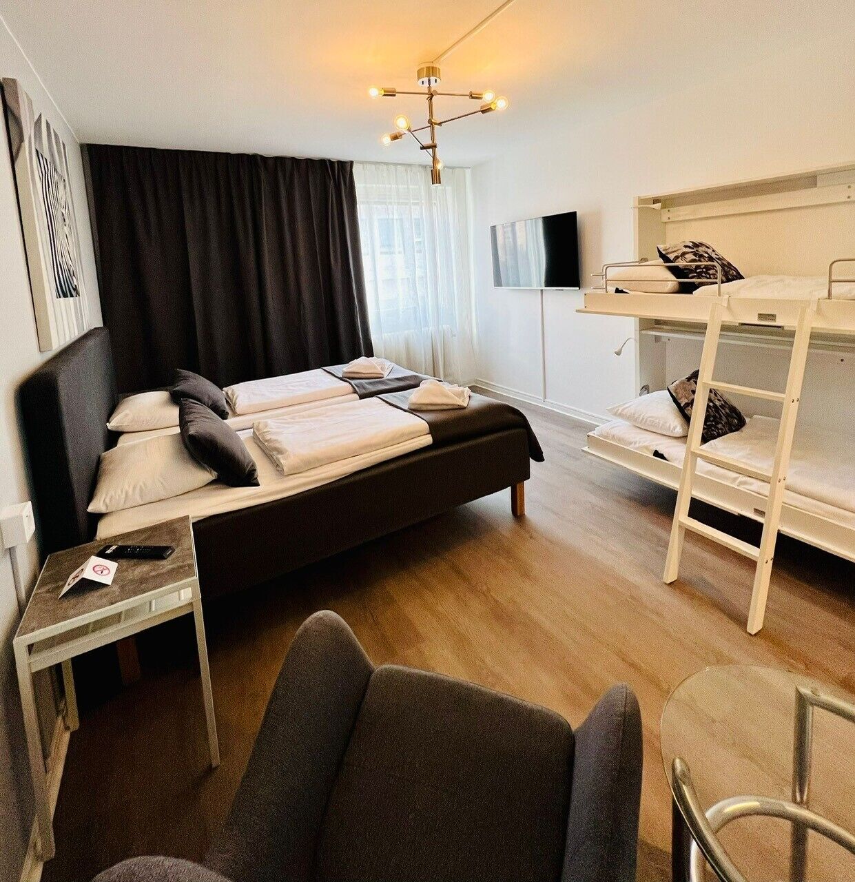 Une chambre d’hôtel de taille réduite, comprenant un lit simple, un lit superposé, un bureau et une chaise.
