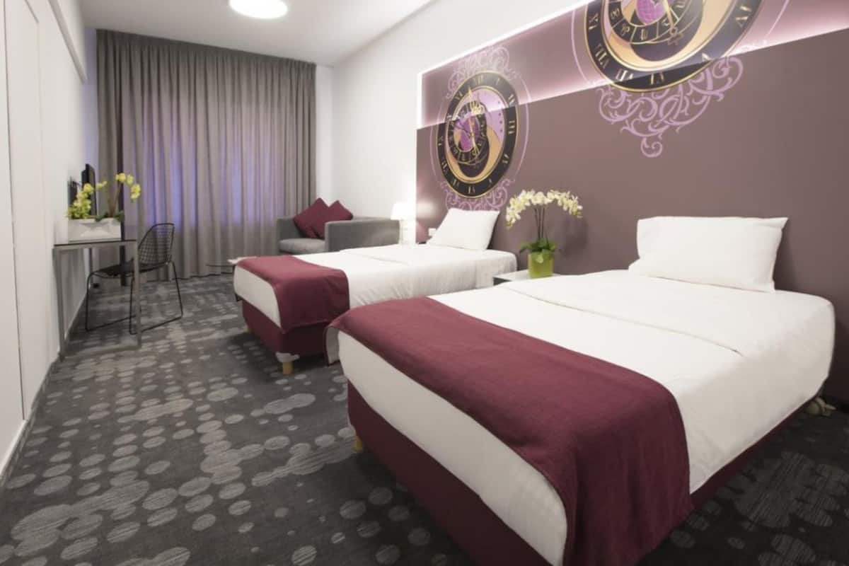 Ein Hotelzimmer mit zwei Betten, einem Schreibtisch und einem Stuhl.