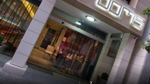 L’entrée d’un hôtel, avec une enseigne au néon indiquant « 35 CHAMBRES ».
