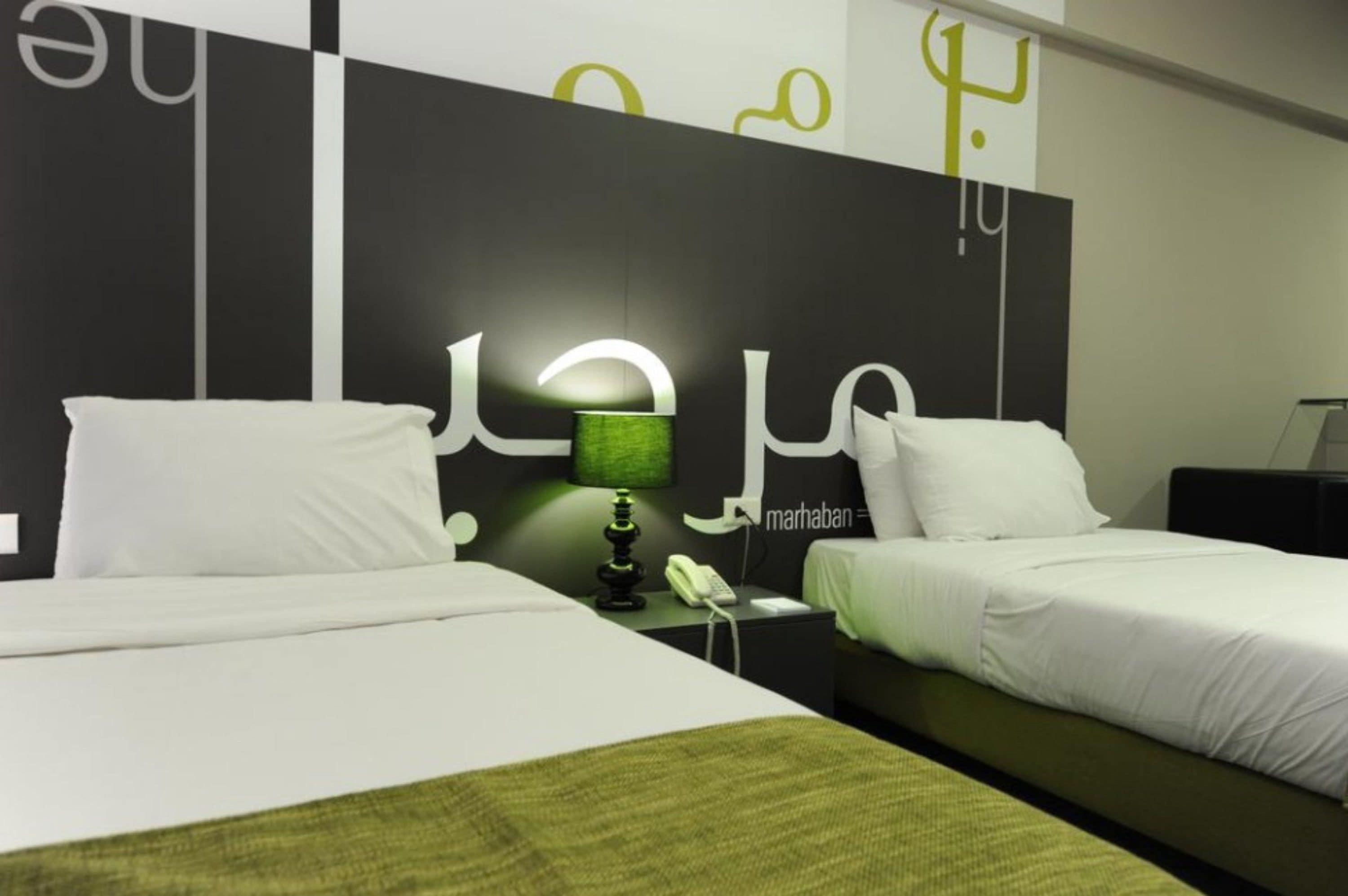 A hotel room with two beds, a nightstand with a lamp, and a wall with abstract art.