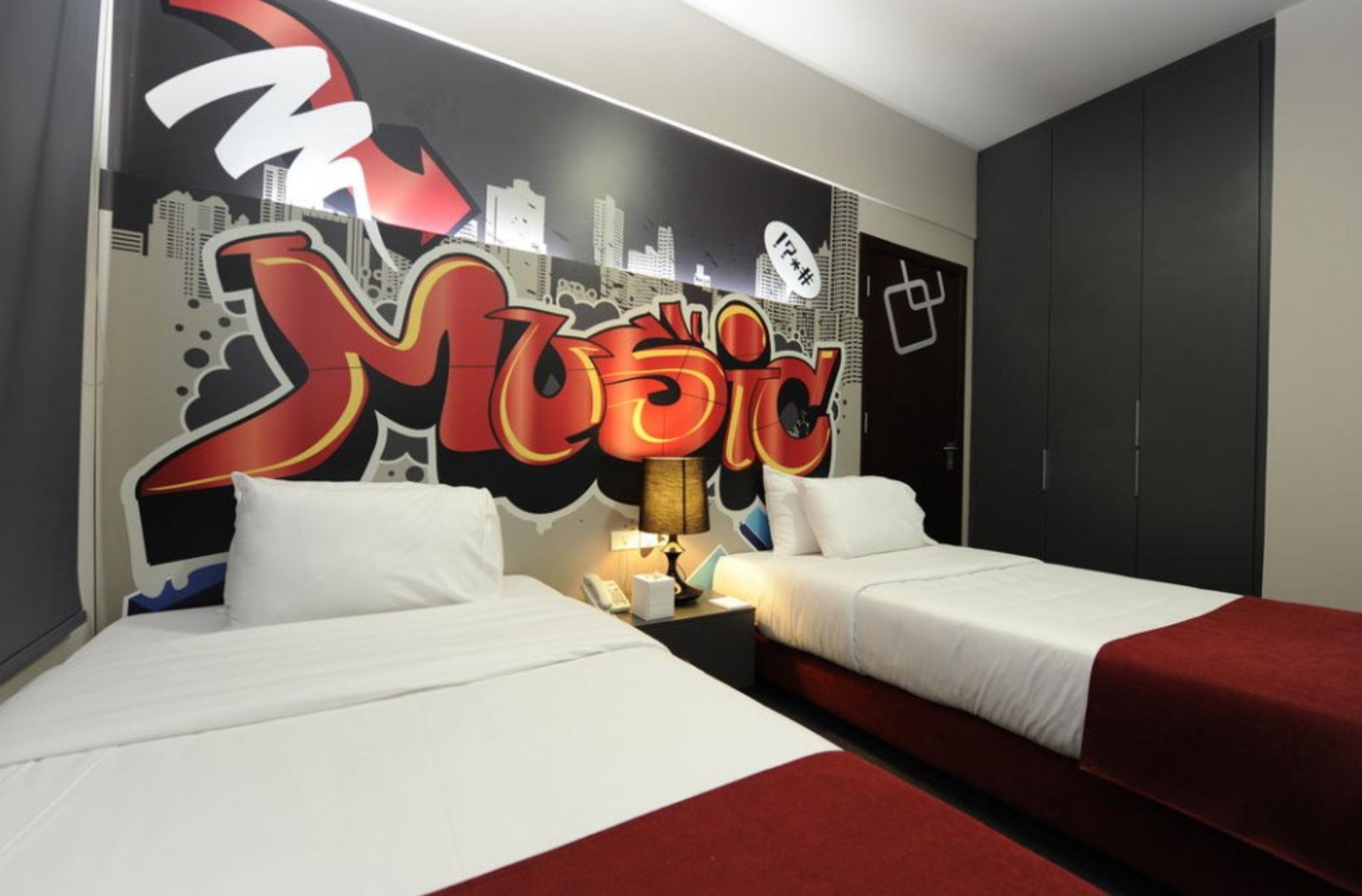 A hotel room with two beds, a cityscape mural, and a wardrobe.
