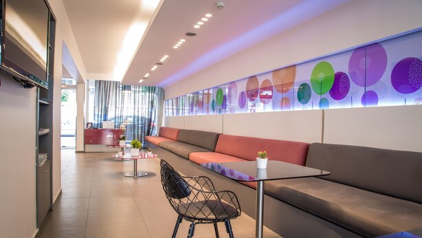 Un hall d’hôtel moderne avec un long canapé, une table en verre et un fauteuil.