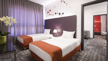 A hotel room with two beds, a large window with curtains, a wall art piece, and a potted plant.
