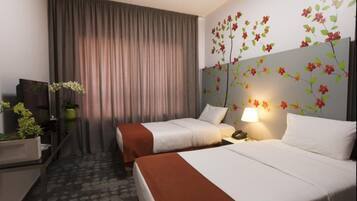 Habitación de hotel con dos camas, un ventanal con cortinas, una pared con una obra de arte floral y un escritorio con lámpara y teléfono.