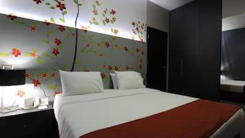 Een moderne hotelkamer met een groot bed, een nachtkastje met telefoon en lamp, en een garderobe.
