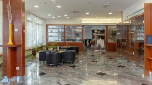 Un vestíbulo con piso de mármol, zona de estar, vitrinas de vidrio y mostrador de recepción.