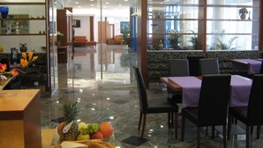 Vestíbulo de hotel con mostrador de recepción, zona de estar y vistas al exterior a través de amplias ventanas.