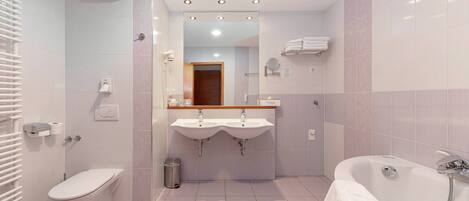 Un baño moderno con inodoro, dos lavamanos, un espejo y una bañera.