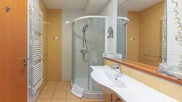A modern bathroom with a glass-enclosed shower, a white sink, and a wooden vanity.