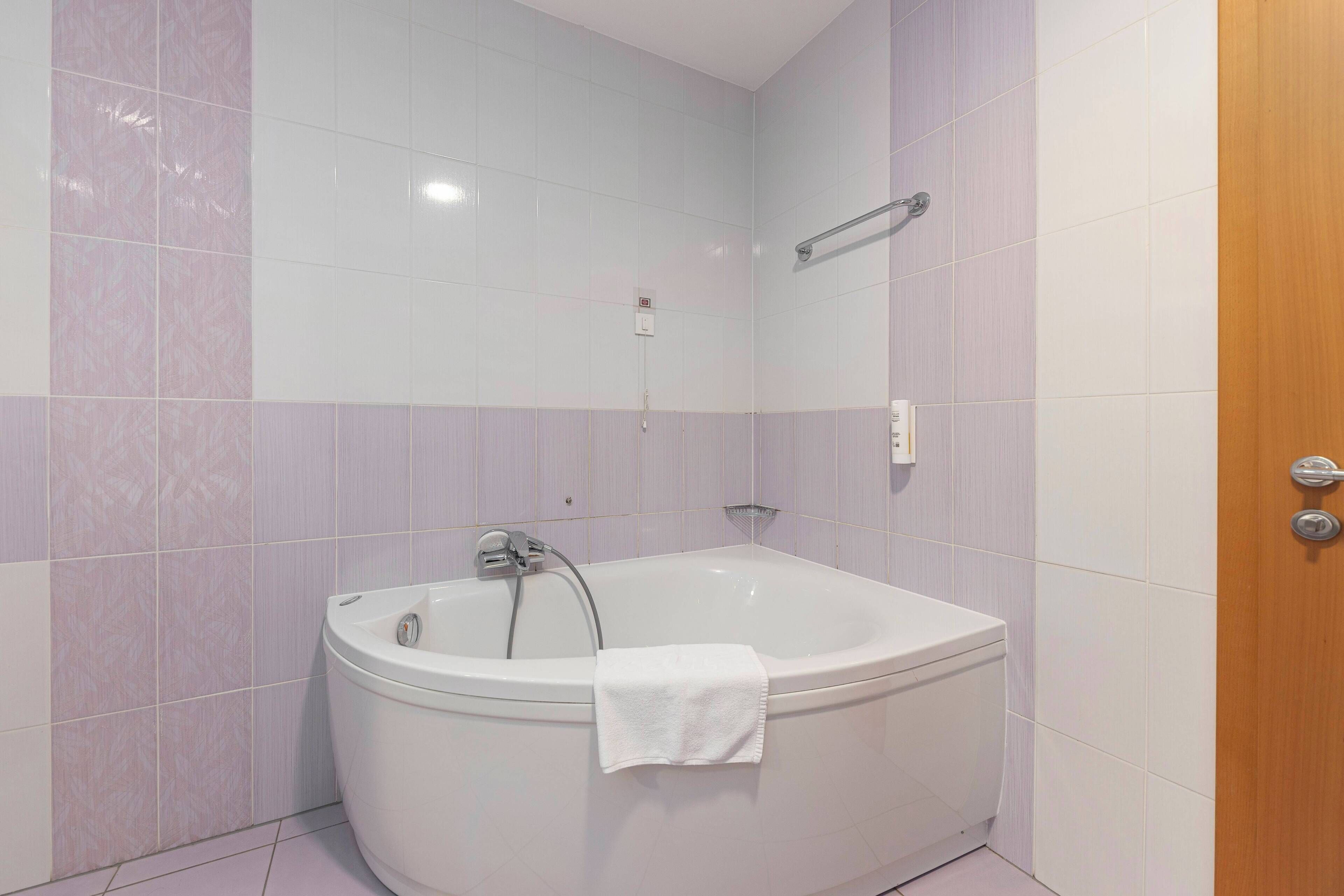 A bathroom with a freestanding bathtub, a towel hanging on the side, and a showerhead.