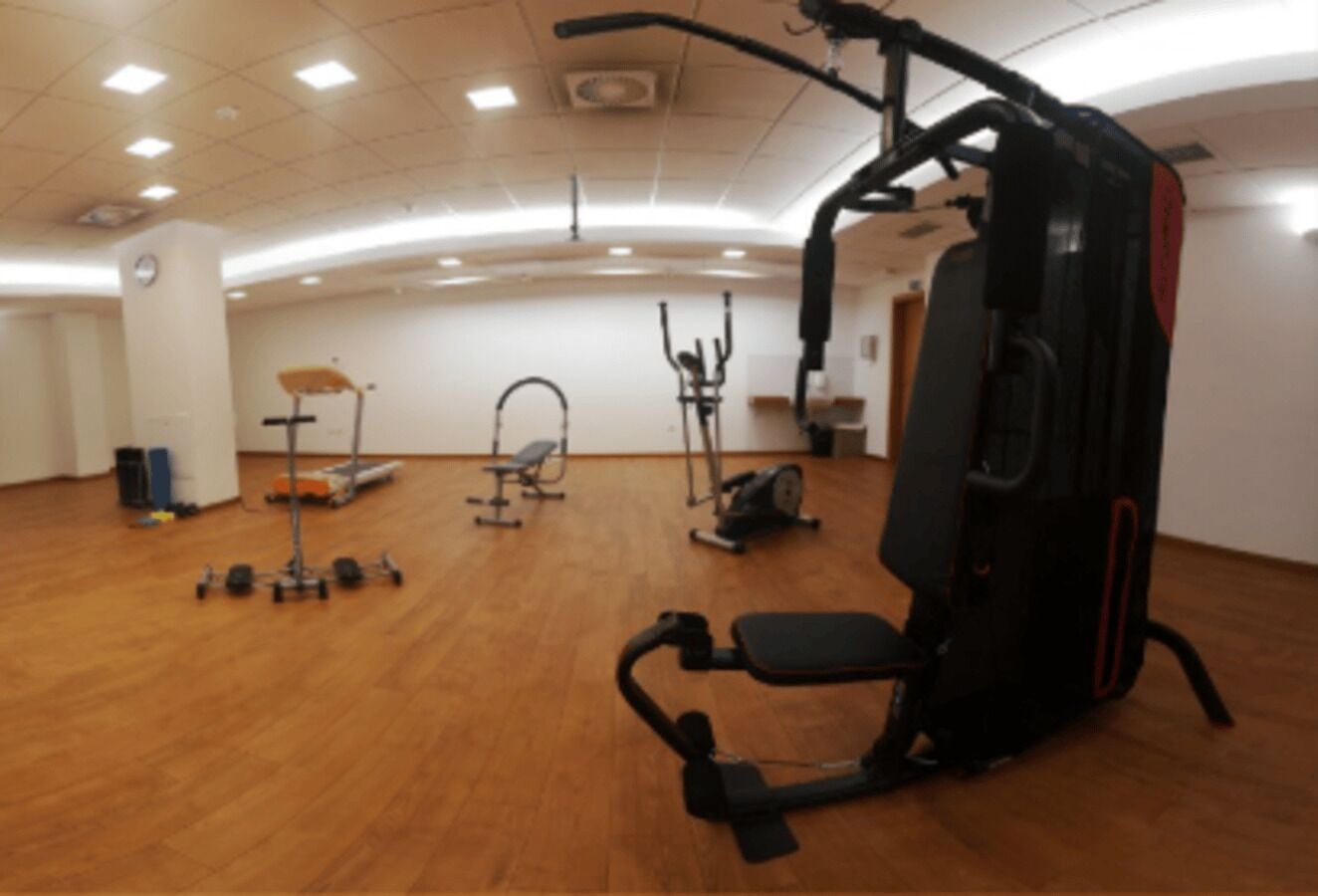 A spacious gym with various exercise equipment, including a treadmill, elliptical, and weight machines.