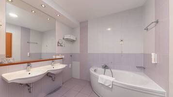 Une salle de bain moderne avec deux lavabos, une baignoire et un grand miroir.