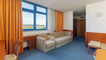 Habitación de hotel con un ventanal grande, un sofá, un escritorio y una silla.