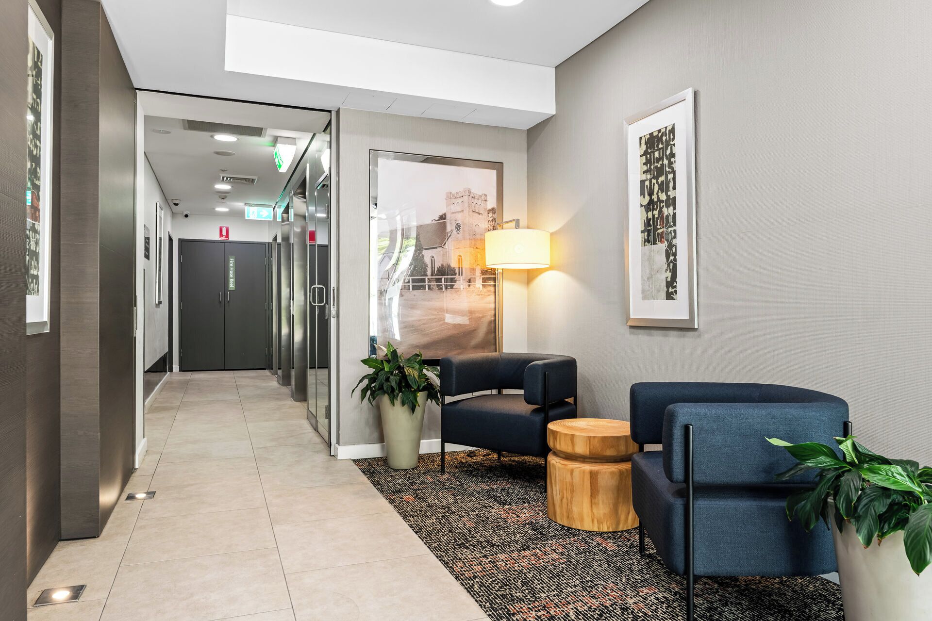 Um lobby moderno com área de estar, uma luminária e um quadro na parede.