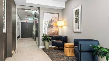 A modern lobby with a seating area, a lamp, and a framed picture on the wall.